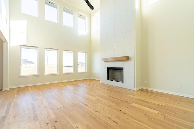 4334 White Ash Dr, Piedmont, OK 73078 - unfurnished living room featuring wood-type flooring, a towering ceiling, a tile fireplace, and a ceiling fan