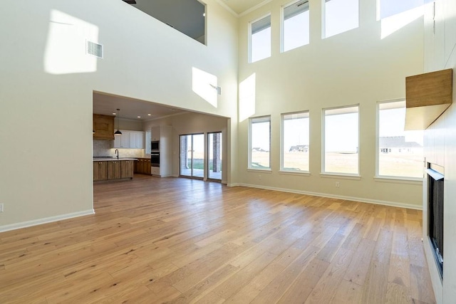 4334 White Ash Dr, Piedmont, OK 73078 - unfurnished living room with light wood-type flooring, crown molding, and a high ceiling