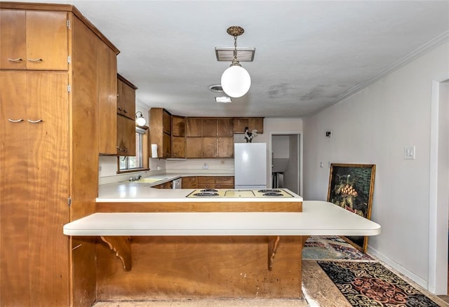 2299 Coretta Ave, Duncan, OK 73534 - kitchen with freestanding refrigerator, light countertops, a peninsula, brown cabinetry, and a breakfast bar area