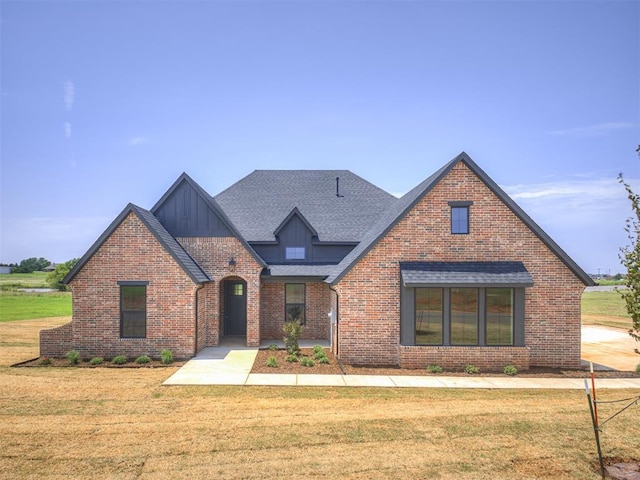6881 Lake View Ct, Cashion, OK 73016 - tudor-style house featuring a front lawn, brick siding, a shingled roof, and board and batten siding