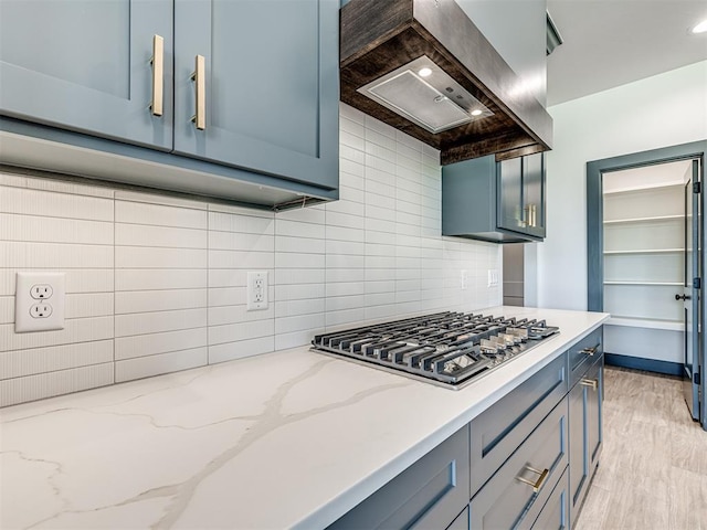 6881 Lake View Ct, Cashion, OK 73016 - kitchen with stainless steel gas cooktop, wall chimney exhaust hood, tasteful backsplash, and light stone countertops