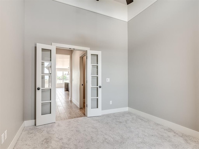 6881 Lake View Ct, Cashion, OK 73016 - carpeted empty room featuring french doors, a ceiling fan, and a towering ceiling