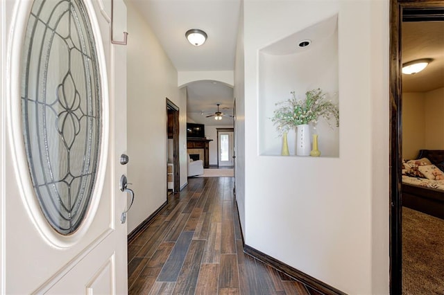 2305 Makaila Way, Yukon, OK 73099 - foyer featuring a fireplace, a ceiling fan, arched walkways, and dark wood-style flooring