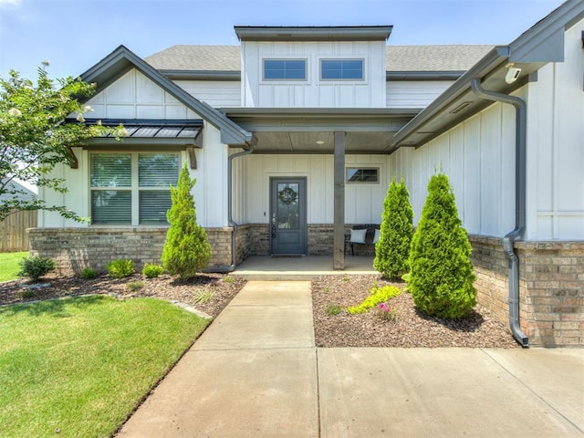 1391 Hickory Trl, Piedmont, OK 73078 - view of exterior entry featuring covered porch, board and batten siding, a shingled roof, and a yard