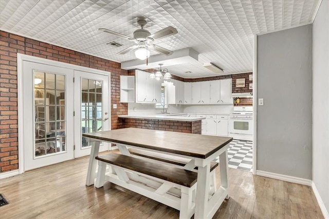 601 N Dobbs Rd, Harrah, OK 73045 - kitchen with white range oven, brick wall, white cabinetry, light countertops, and a ceiling fan