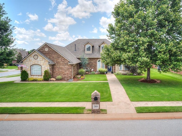 2009 Pembroke Ln, Edmond, OK 73003 - view of front of property featuring a front yard, stone siding, brick siding, and a shingled roof