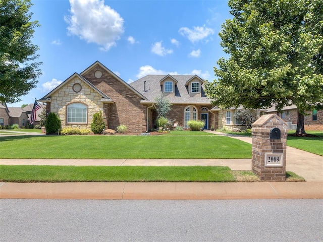2009 Pembroke Ln, Edmond, OK 73003 - view of front facade with a front lawn, stone siding, and brick siding