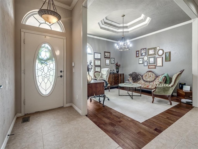 2009 Pembroke Ln, Edmond, OK 73003 - foyer entrance with plenty of natural light, a chandelier, a raised ceiling, tile patterned floors, and crown molding