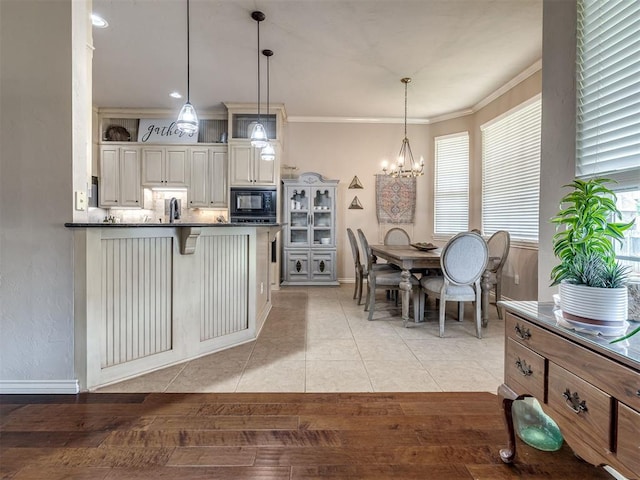 2009 Pembroke Ln, Edmond, OK 73003 - kitchen featuring dark countertops, black microwave, a kitchen bar, a chandelier, and plenty of natural light
