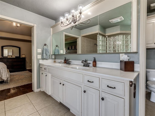 2009 Pembroke Ln, Edmond, OK 73003 - ensuite bathroom featuring double vanity, tile patterned flooring, tiled shower, and a chandelier