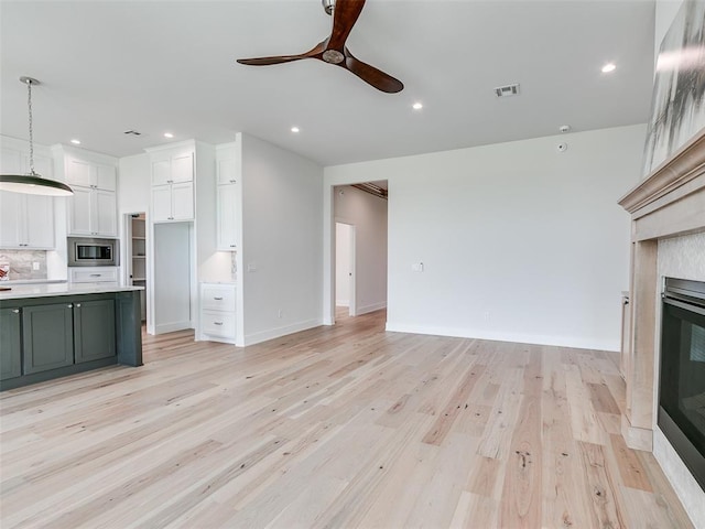 216 Pont Neuf Ct, Edmond, OK 73034 - kitchen with white cabinetry, open floor plan, light countertops, a ceiling fan, and light wood-style flooring
