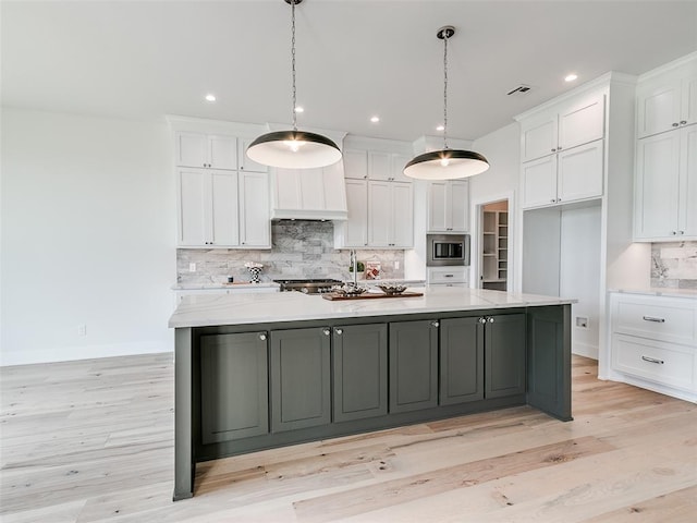 216 Pont Neuf Ct, Edmond, OK 73034 - kitchen featuring stainless steel microwave, white cabinets, tasteful backsplash, light wood-style flooring, and recessed lighting
