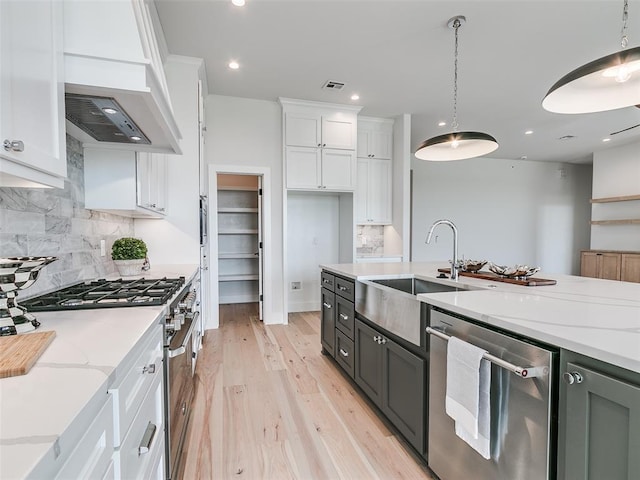 216 Pont Neuf Ct, Edmond, OK 73034 - kitchen with appliances with stainless steel finishes, white cabinets, decorative backsplash, light wood-style floors, and light stone countertops