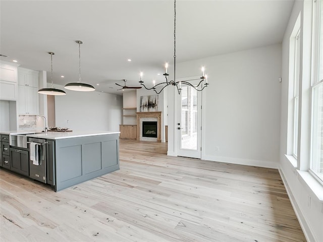 216 Pont Neuf Ct, Edmond, OK 73034 - kitchen featuring open floor plan, light countertops, dishwasher, white cabinetry, and light wood-style flooring