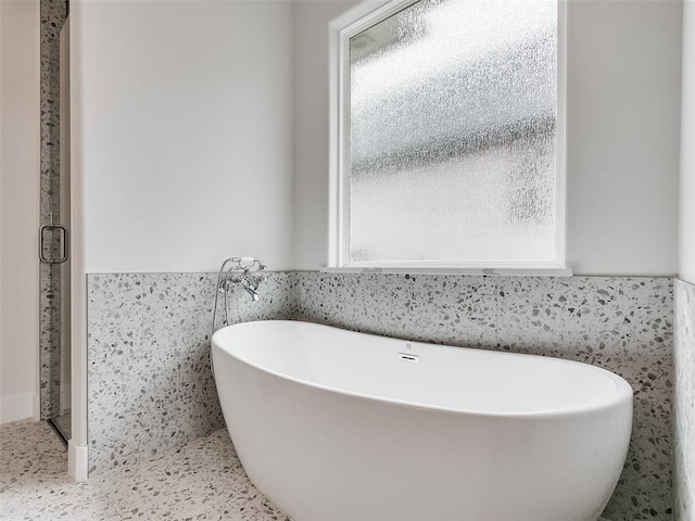 216 Pont Neuf Ct, Edmond, OK 73034 - bathroom with healthy amount of natural light, a soaking tub, a wainscoted wall, and tile walls