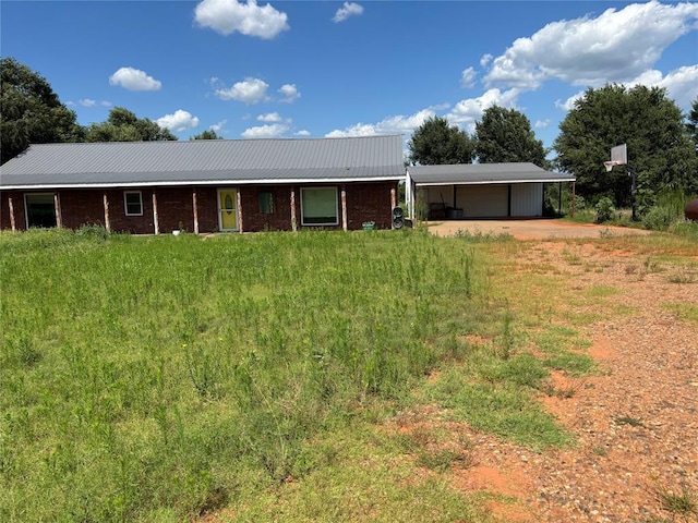 single story home with dirt driveway, a carport, a metal roof, and an attached garage