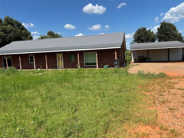 ranch-style home with a garage, a metal roof, an outbuilding, brick siding, and concrete driveway