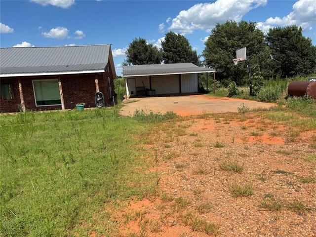 view of yard with an outdoor structure, driveway, and a detached garage