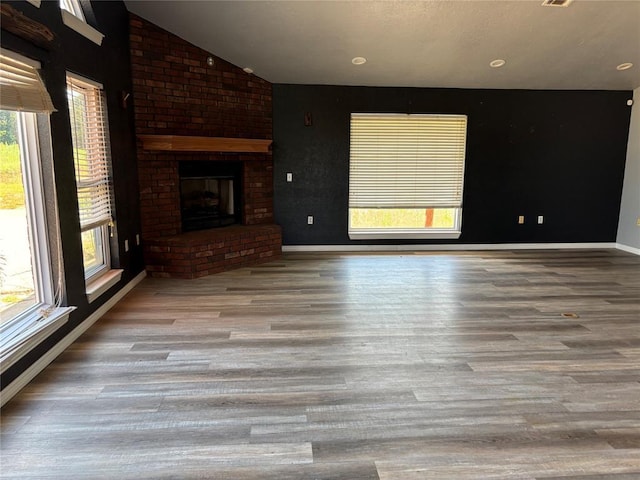 unfurnished living room featuring wood finished floors, a fireplace, and lofted ceiling