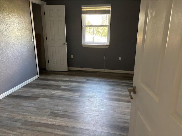 empty room featuring wood finished floors and baseboards