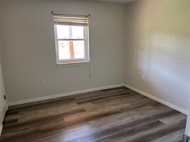unfurnished room featuring baseboards and dark wood-style floors