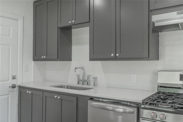 1120 SW 47th St, Oklahoma City, OK 73109 - kitchen with stainless steel appliances, gray cabinets, under cabinet range hood, and decorative backsplash