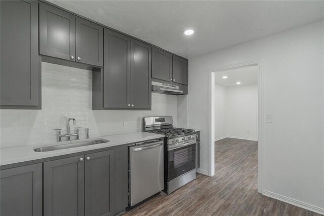 1120 SW 47th St, Oklahoma City, OK 73109 - kitchen with appliances with stainless steel finishes, under cabinet range hood, dark wood-style floors, tasteful backsplash, and light countertops