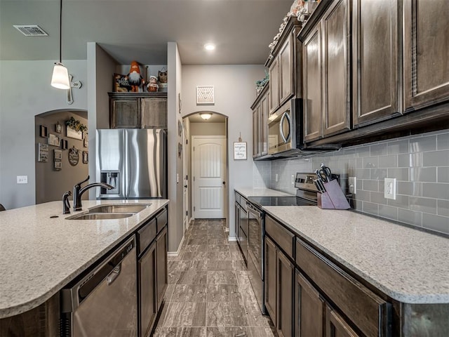 12812 Double V Dr, Piedmont, OK 73078 - kitchen with stainless steel appliances, arched walkways, dark brown cabinetry, and decorative backsplash