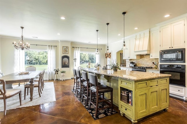 775 Magnolia Ln, Tuttle, OK 73089 - kitchen with black appliances, premium range hood, a chandelier, tasteful backsplash, and a kitchen island