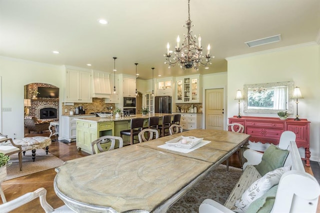 775 Magnolia Ln, Tuttle, OK 73089 - dining room with recessed lighting, a chandelier, crown molding, dark wood-type flooring, and a brick fireplace