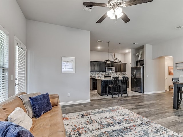 3529 Slate River Dr, Yukon, OK 73099 - living area with arched walkways, a ceiling fan, and light wood-type flooring