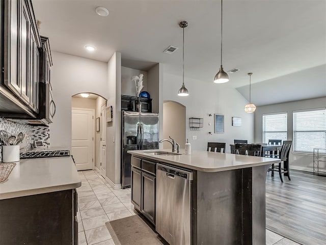 3529 Slate River Dr, Yukon, OK 73099 - kitchen with stainless steel appliances, arched walkways, tasteful backsplash, lofted ceiling, and decorative light fixtures