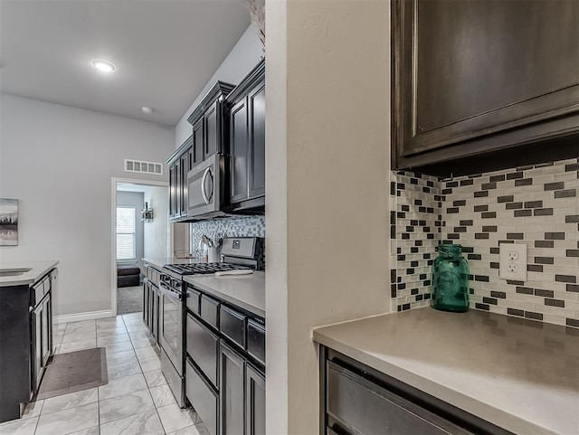 3529 Slate River Dr, Yukon, OK 73099 - kitchen featuring appliances with stainless steel finishes, backsplash, light countertops, and light marble finish floors