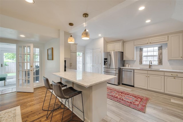1114 Glenwood Ave, Nichols Hills, OK 73116 - kitchen featuring appliances with stainless steel finishes, lofted ceiling, backsplash, a kitchen bar, and light wood-style floors