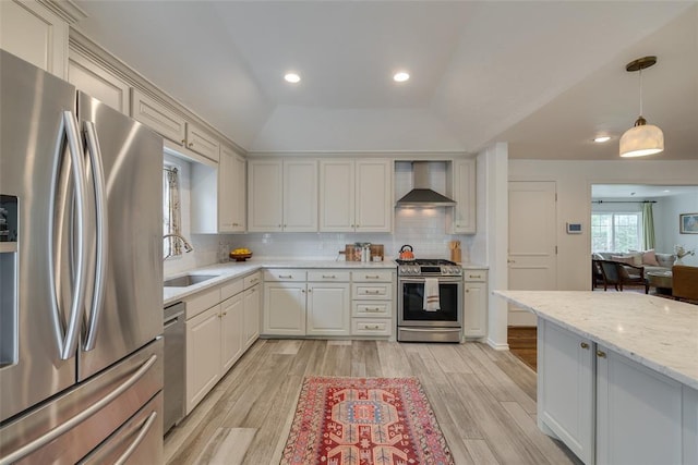 1114 Glenwood Ave, Nichols Hills, OK 73116 - kitchen featuring appliances with stainless steel finishes, wall chimney range hood, light wood-style floors, backsplash, and decorative light fixtures