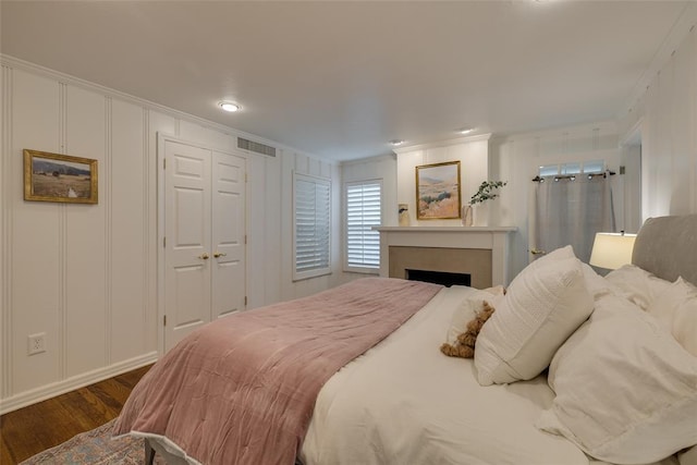 1114 Glenwood Ave, Nichols Hills, OK 73116 - bedroom with dark wood-type flooring, ornamental molding, a decorative wall, a fireplace, and a closet