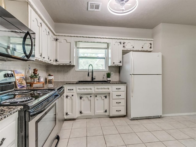 3013 Beverly Dr, Edmond, OK 73013 - kitchen featuring freestanding refrigerator, stainless steel electric stove, black microwave, white cabinets, and tasteful backsplash
