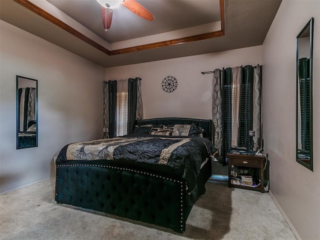 carpeted bedroom featuring a tray ceiling and a ceiling fan