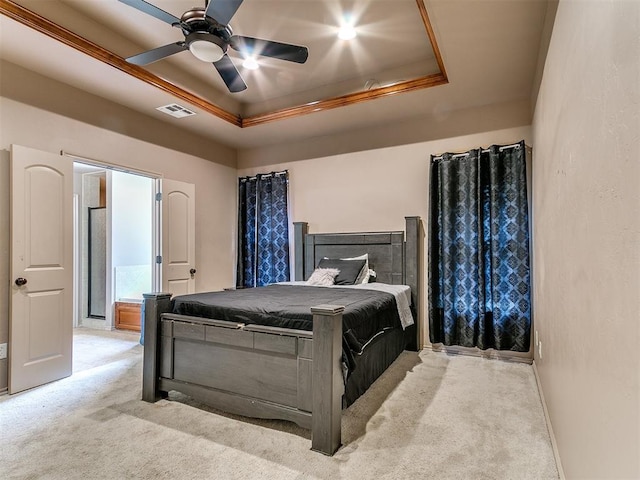 bedroom with light carpet, a tray ceiling, ornamental molding, and a ceiling fan