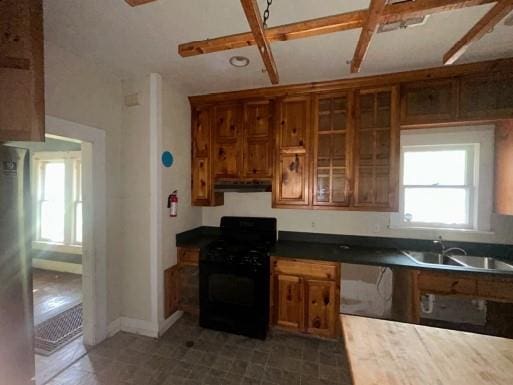 1217 W Main St, Ardmore, OK 73401 - kitchen featuring black range with gas stovetop, under cabinet range hood, brown cabinetry, and glass insert cabinets