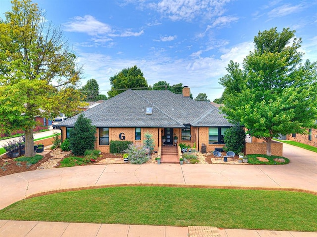 1521 Spring Creek Dr, Yukon, OK 73099 - view of front of home with curved driveway, a front yard, a chimney, and a shingled roof