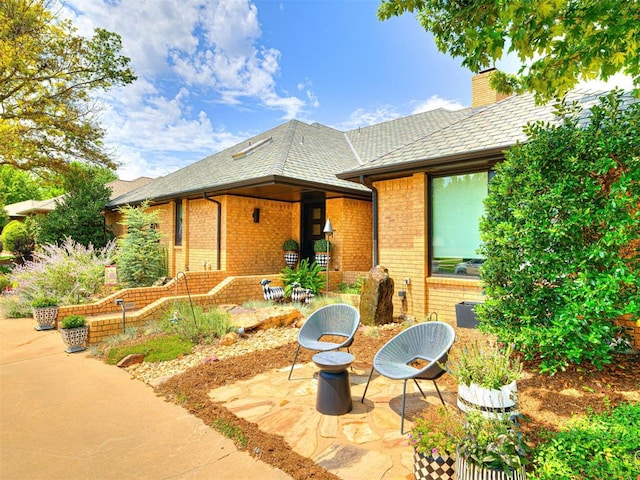 1521 Spring Creek Dr, Yukon, OK 73099 - view of front of home featuring a patio, brick siding, and a chimney
