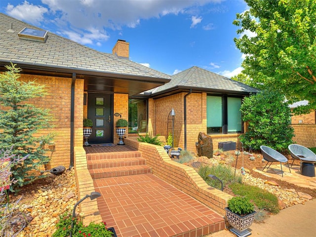 1521 Spring Creek Dr, Yukon, OK 73099 - view of exterior entry featuring brick siding and a chimney