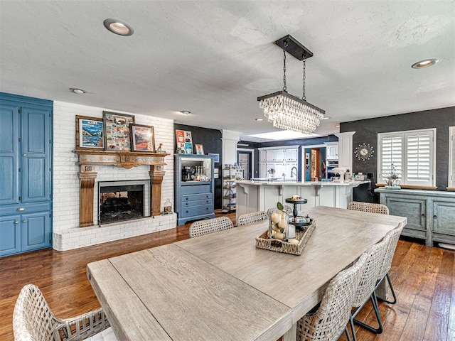 1521 Spring Creek Dr, Yukon, OK 73099 - dining space with decorative columns, hardwood / wood-style floors, a brick fireplace, recessed lighting, and a chandelier