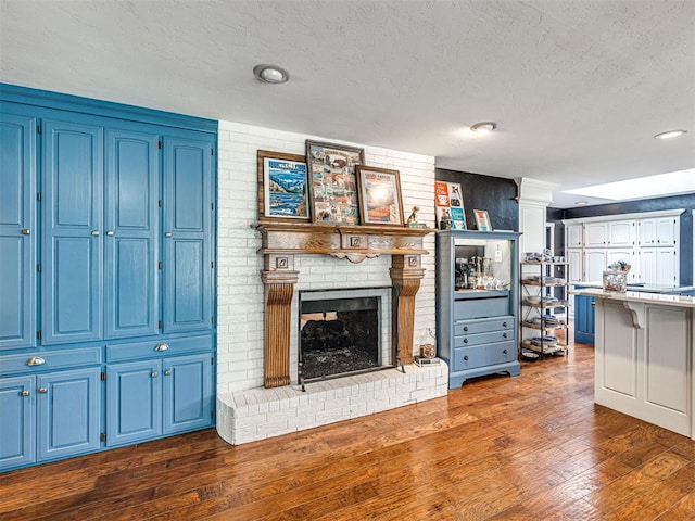1521 Spring Creek Dr, Yukon, OK 73099 - living area featuring dark wood-style flooring, a fireplace, a textured ceiling, ornate columns, and recessed lighting