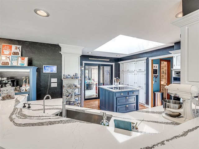 1521 Spring Creek Dr, Yukon, OK 73099 - kitchen featuring white cabinets, blue cabinetry, a skylight, black electric cooktop, and decorative columns