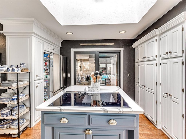 1521 Spring Creek Dr, Yukon, OK 73099 - kitchen featuring black electric stovetop, freestanding refrigerator, light wood-style flooring, white cabinets, and light countertops