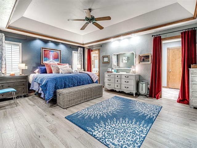 1521 Spring Creek Dr, Yukon, OK 73099 - bedroom featuring a tray ceiling, multiple windows, wood finished floors, and a ceiling fan
