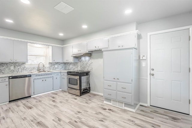 27 NE 65th St, Oklahoma City, OK 73105 - kitchen with appliances with stainless steel finishes, under cabinet range hood, light wood-type flooring, tasteful backsplash, and recessed lighting