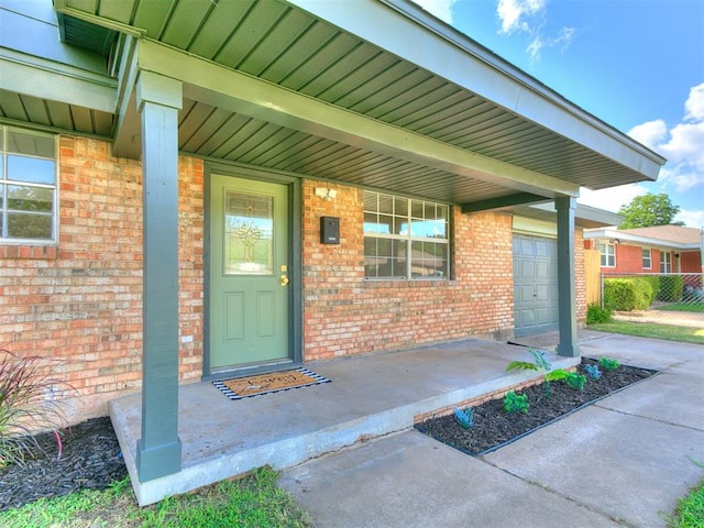 111 S Bristow Ave, Moore, OK 73160 - view of exterior entry featuring a porch, brick siding, a garage, and driveway